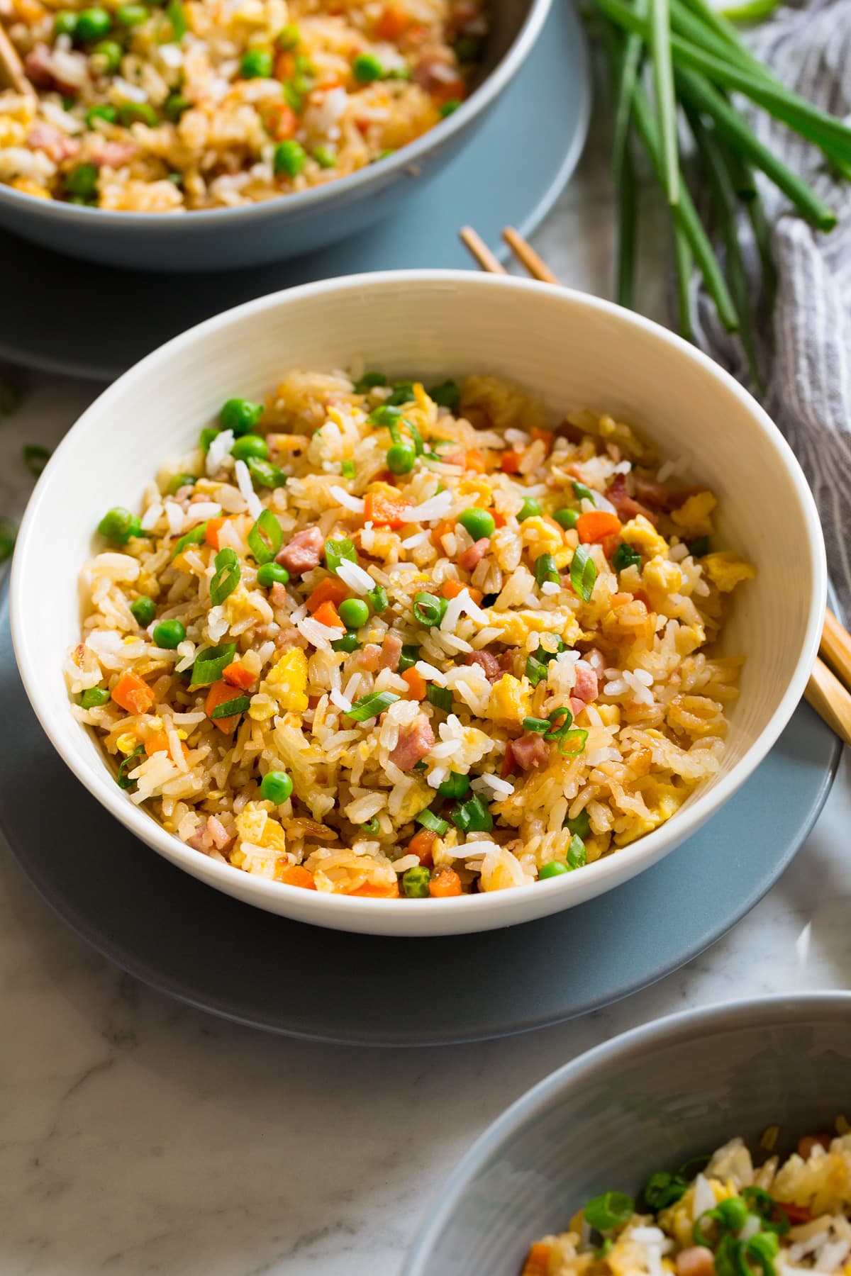 Serving of fried rice in a white bowl set over a blue plate.