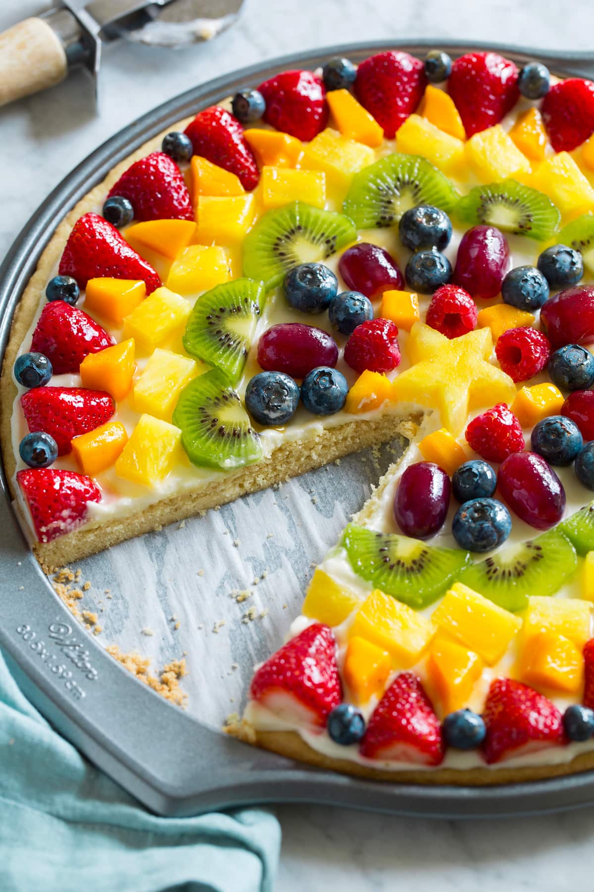 Side view of fruit pizza with one slice removed to show texture of interior.
