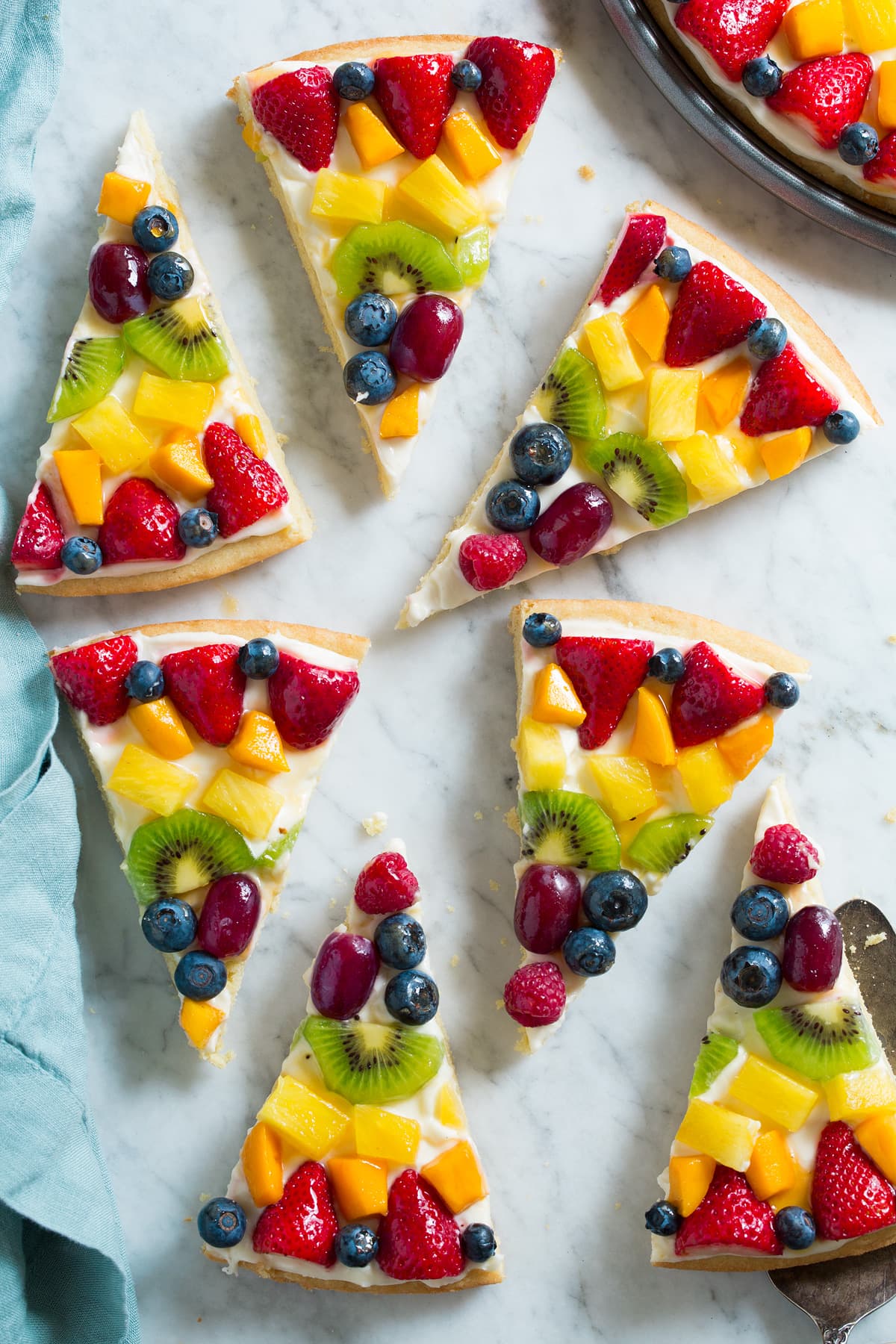 Slices of fruit pizza on a marble surface.