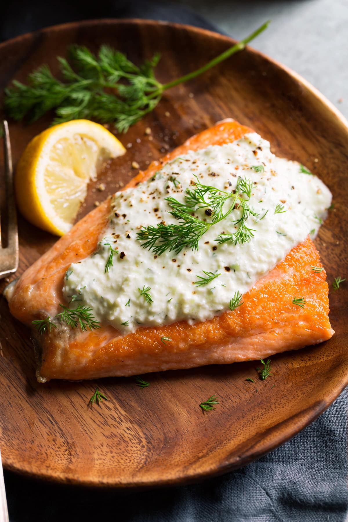 Showing serving suggestion pairing tzatziki sauce atop a salmon fillet.