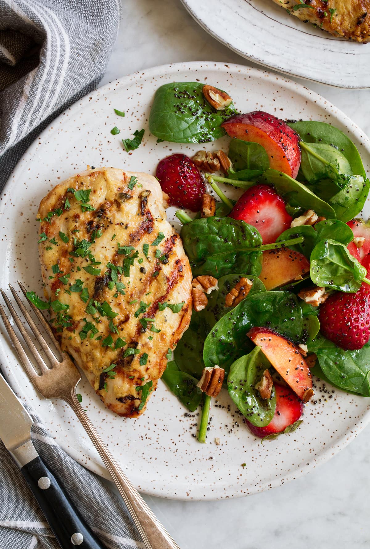 Dijon chicken shown on a serving plate with a side of spinach strawberry salad and poppy seed dressing.