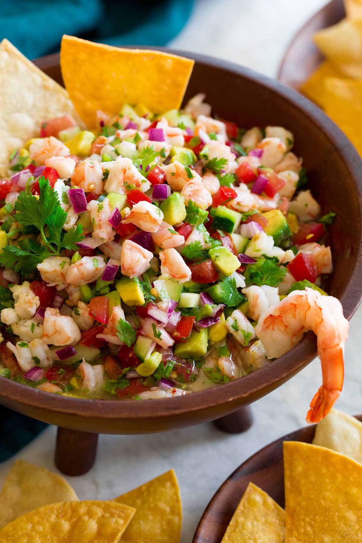 Ceviche in a wooden dip bowl with tortilla chips on the side.