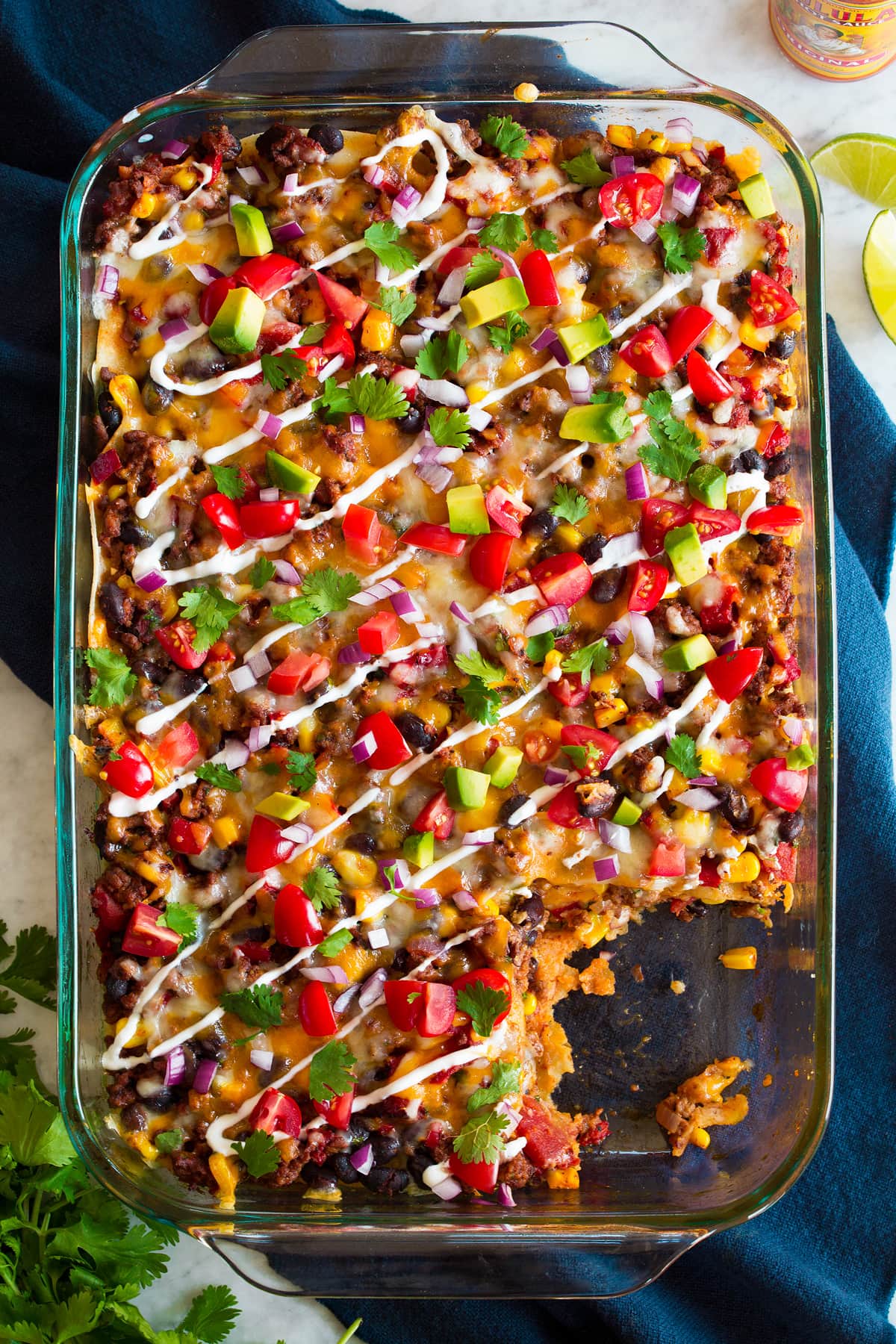 Overhead image of taco casserole in glass baking dish set over a blue cloth.