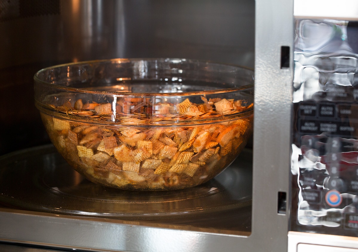 Chex Mix shown in a glass bowl in the microwave before cooking.