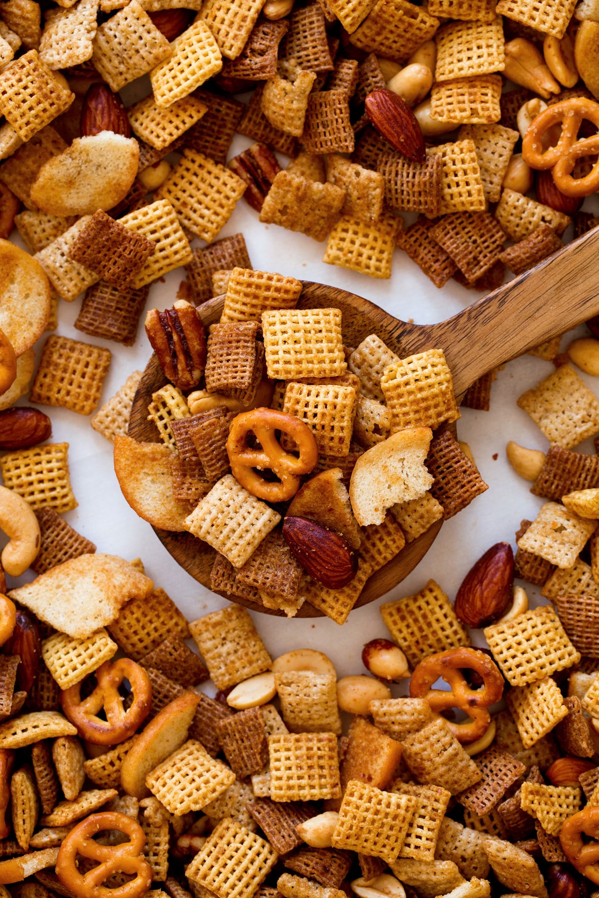 Wood spoon full of Chex Mix shown close up.