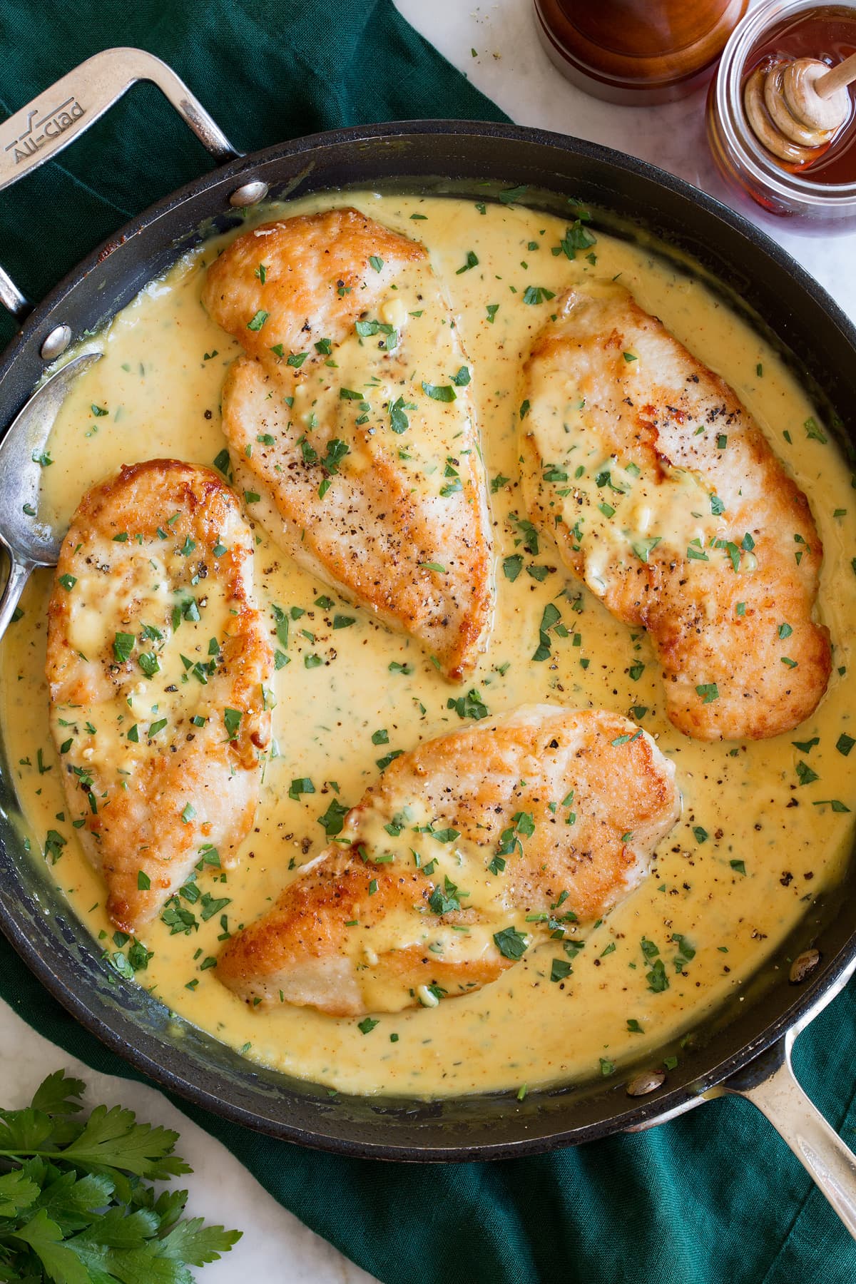 Four chicken breasts in honey mustard sauce in a large black skillet.