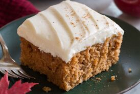 Close up image of single slice of applesauce cake on a green plate with a second slice in the background.