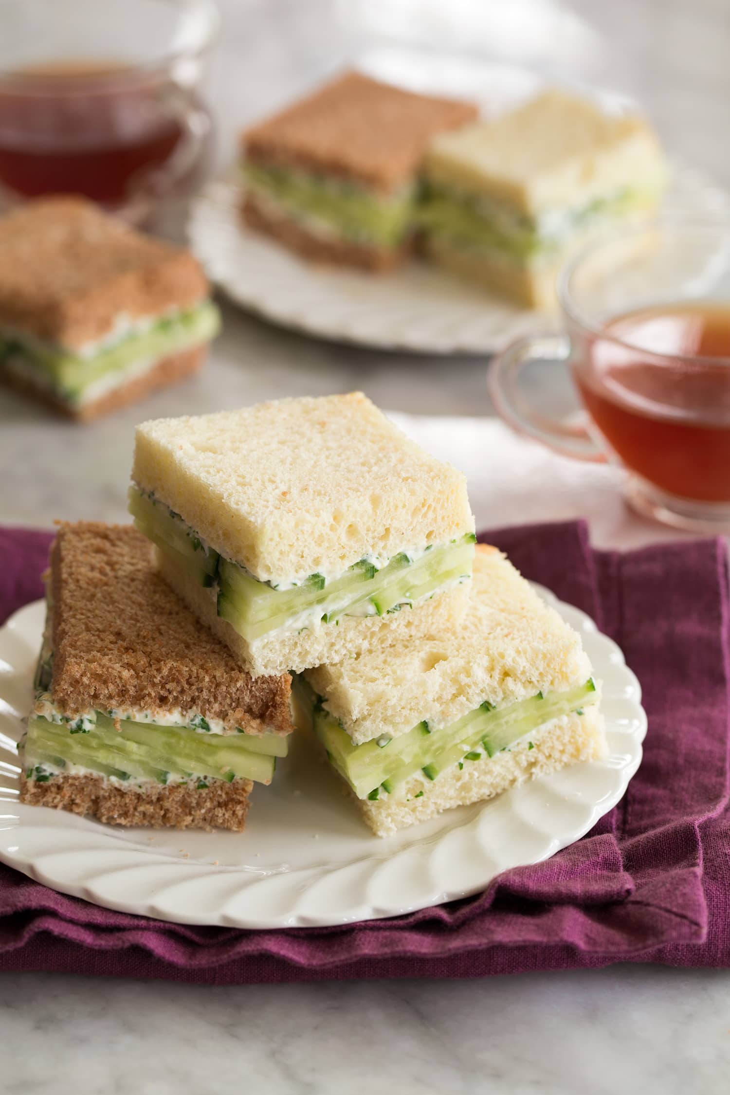 Tea plate with cucumber sandwiches and tea served to the side.