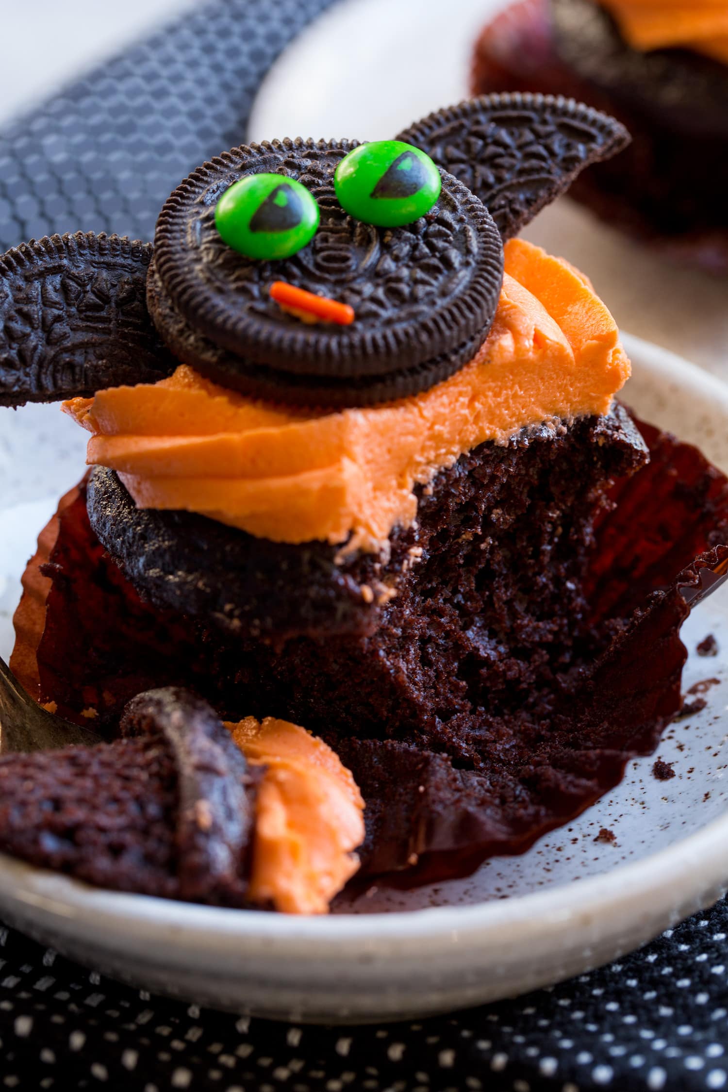 Chocolate cupcake with orange buttercream shown sliced into to see texture.
