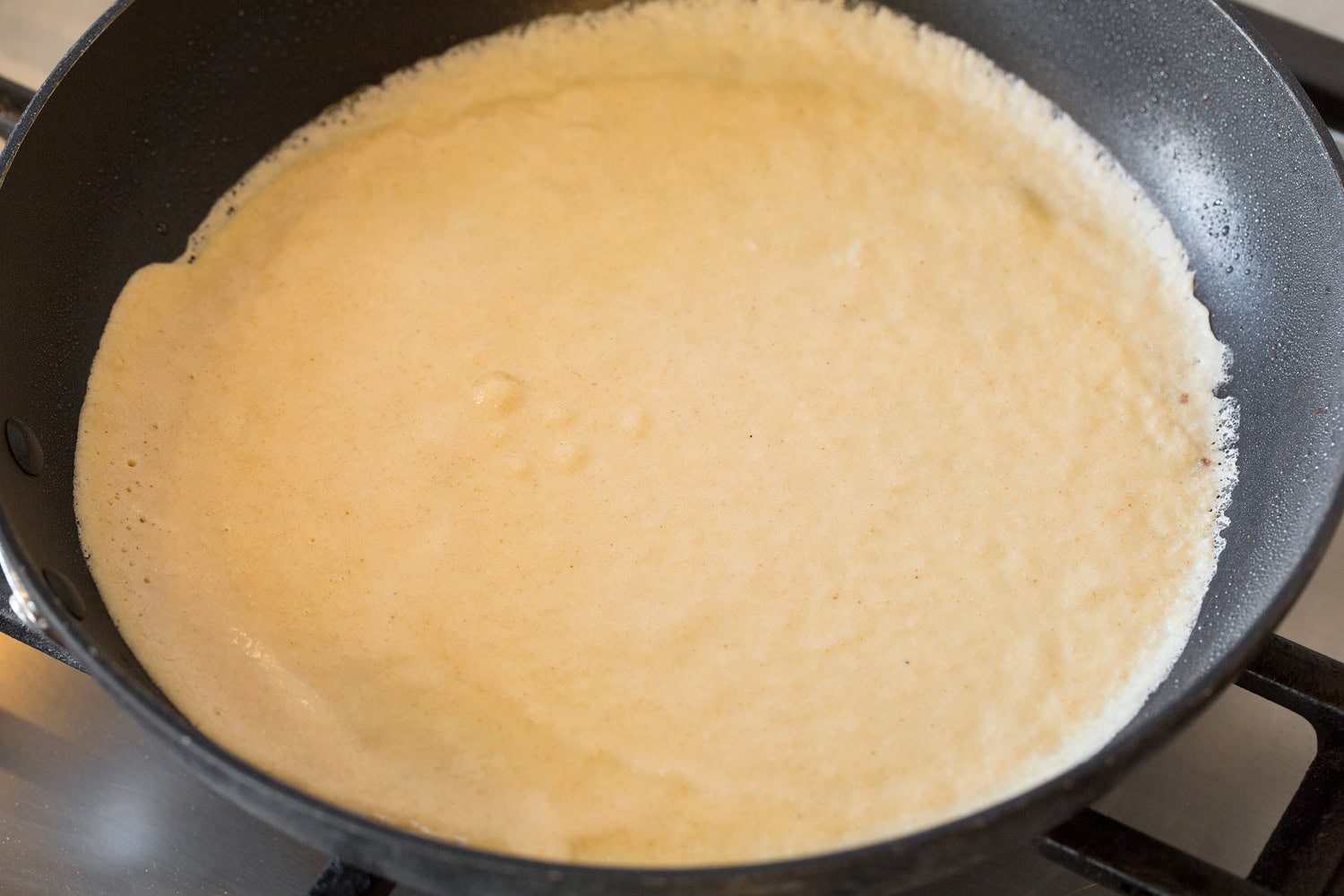 Healthy crepe in non-stick pan shown before flipping.