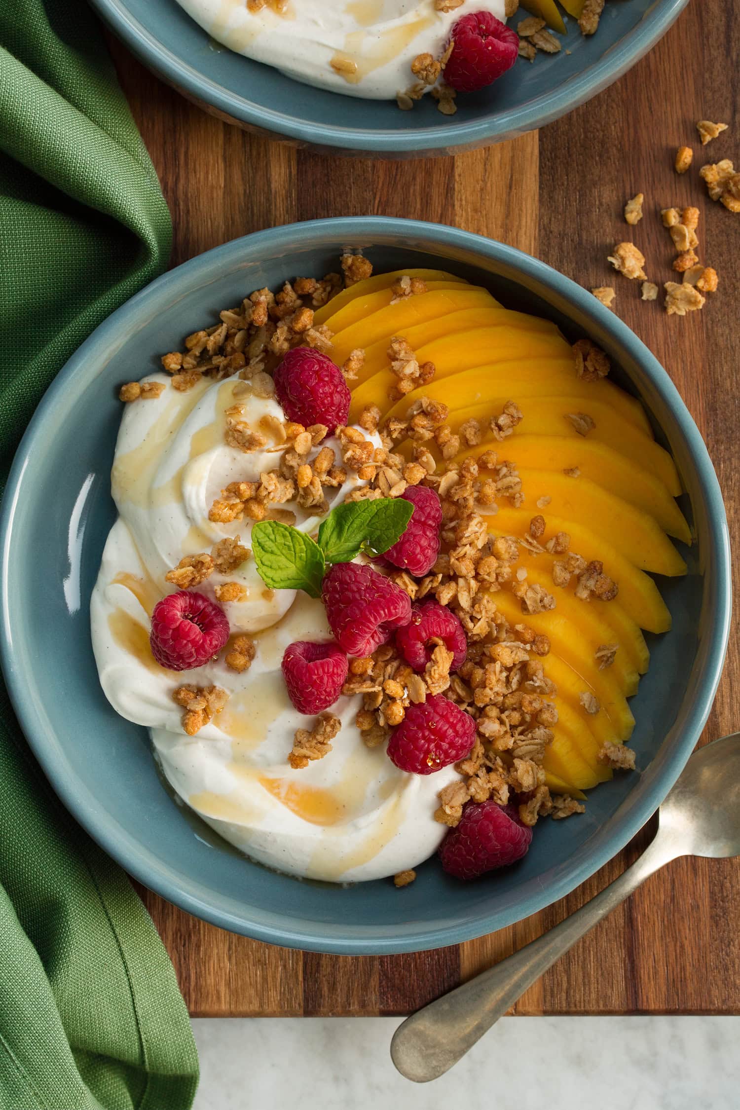 Whipped yogurt served with fruit and yogurt in a blue bowl over a wooden surface.