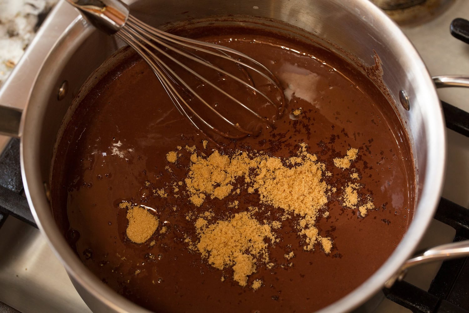 Brown sugar added to melted chocolate and milk mixture in saucepan.
