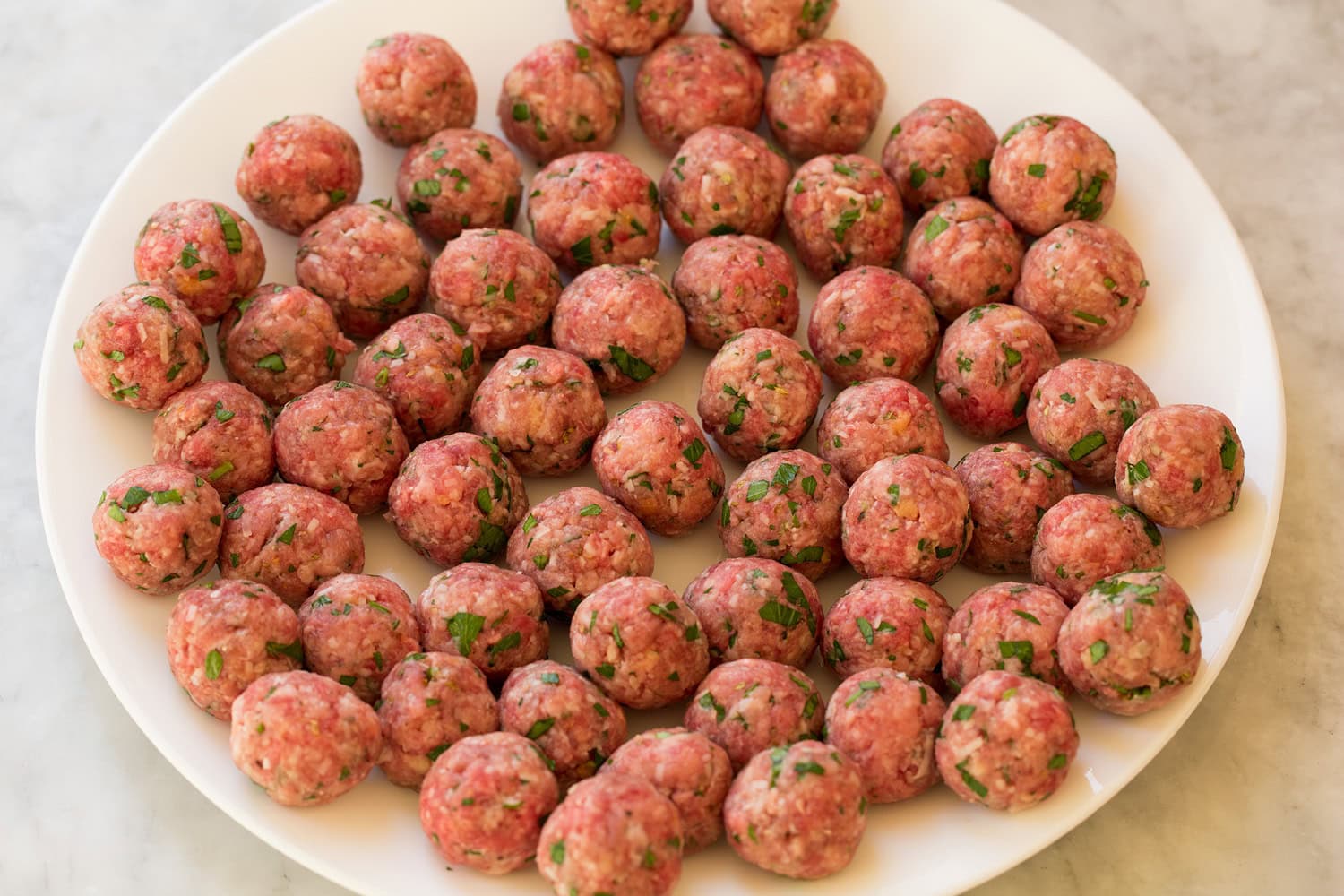 Formed mini Italian meatballs on a large plate.