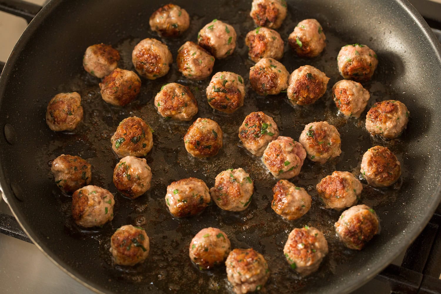 Browned mini meatballs in a skillet.