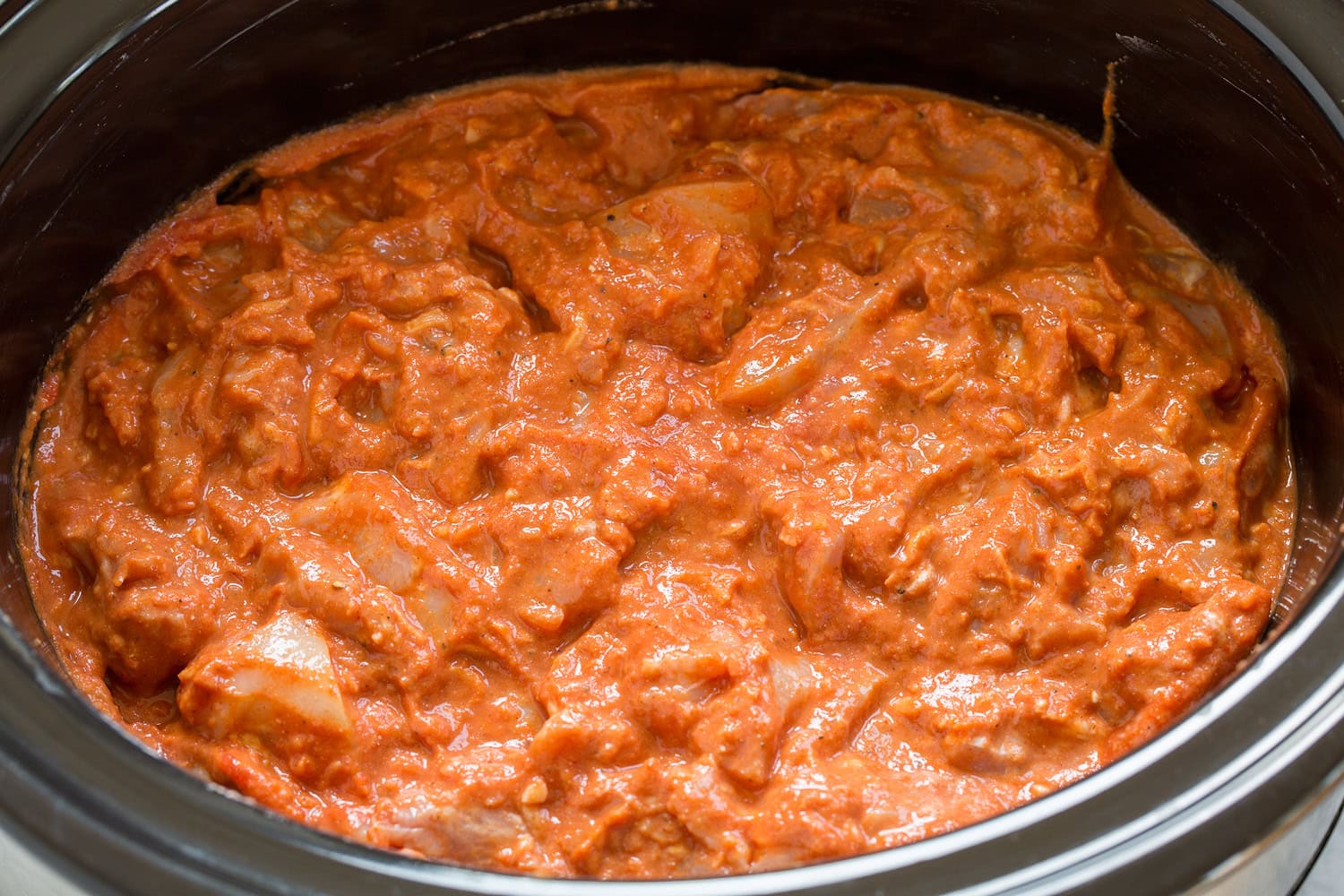Chicken mixture tossed in slow cooker, shown before cooking.