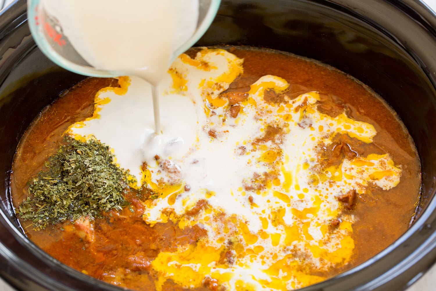Cream and fenugreek added to cooked chicken tikka masala mixture in slow cooker.
