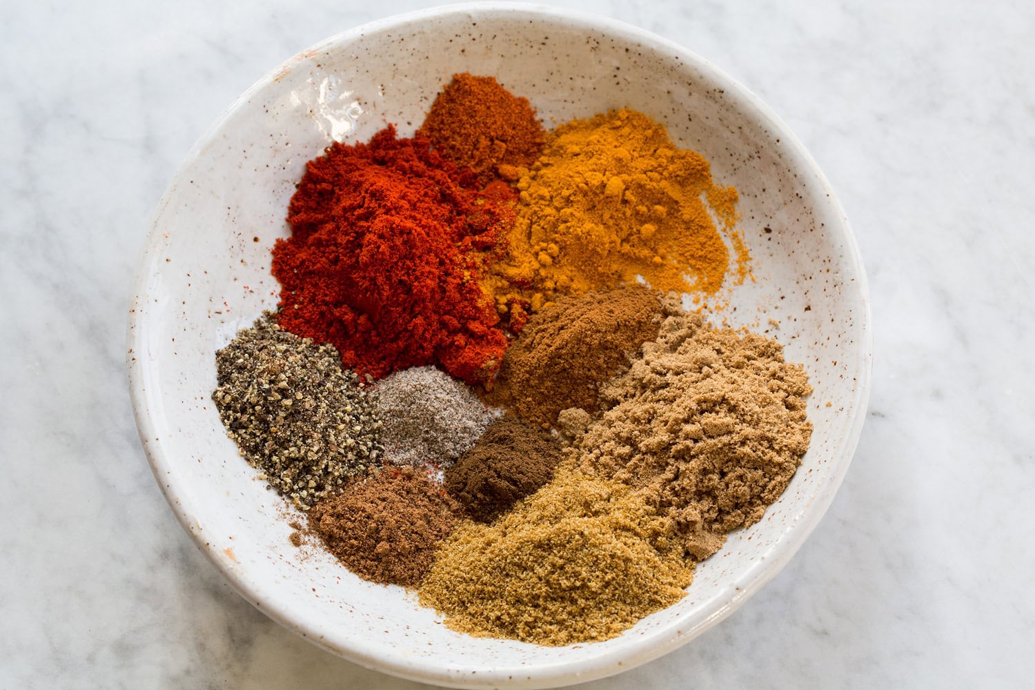 Indian spices in a small white bowl.