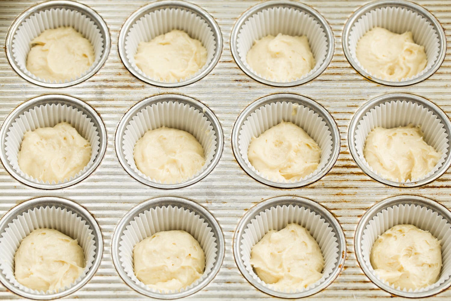 Vanilla portion of cupcake batter added to muffin pan.