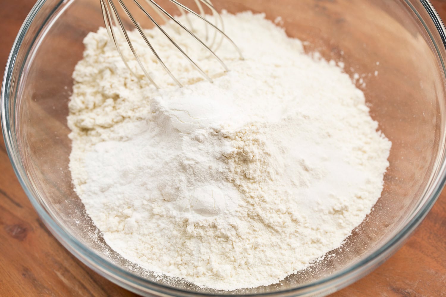 Whisking dry mixture for cupcakes in glass bowl.