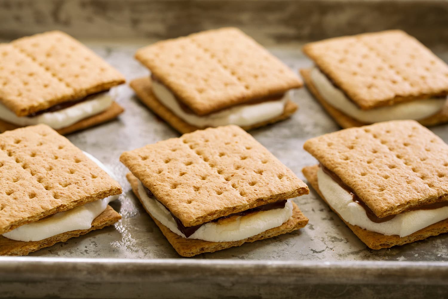 Second graham cracker layered over toasted marshmallow and chocolate to finish s'mores.