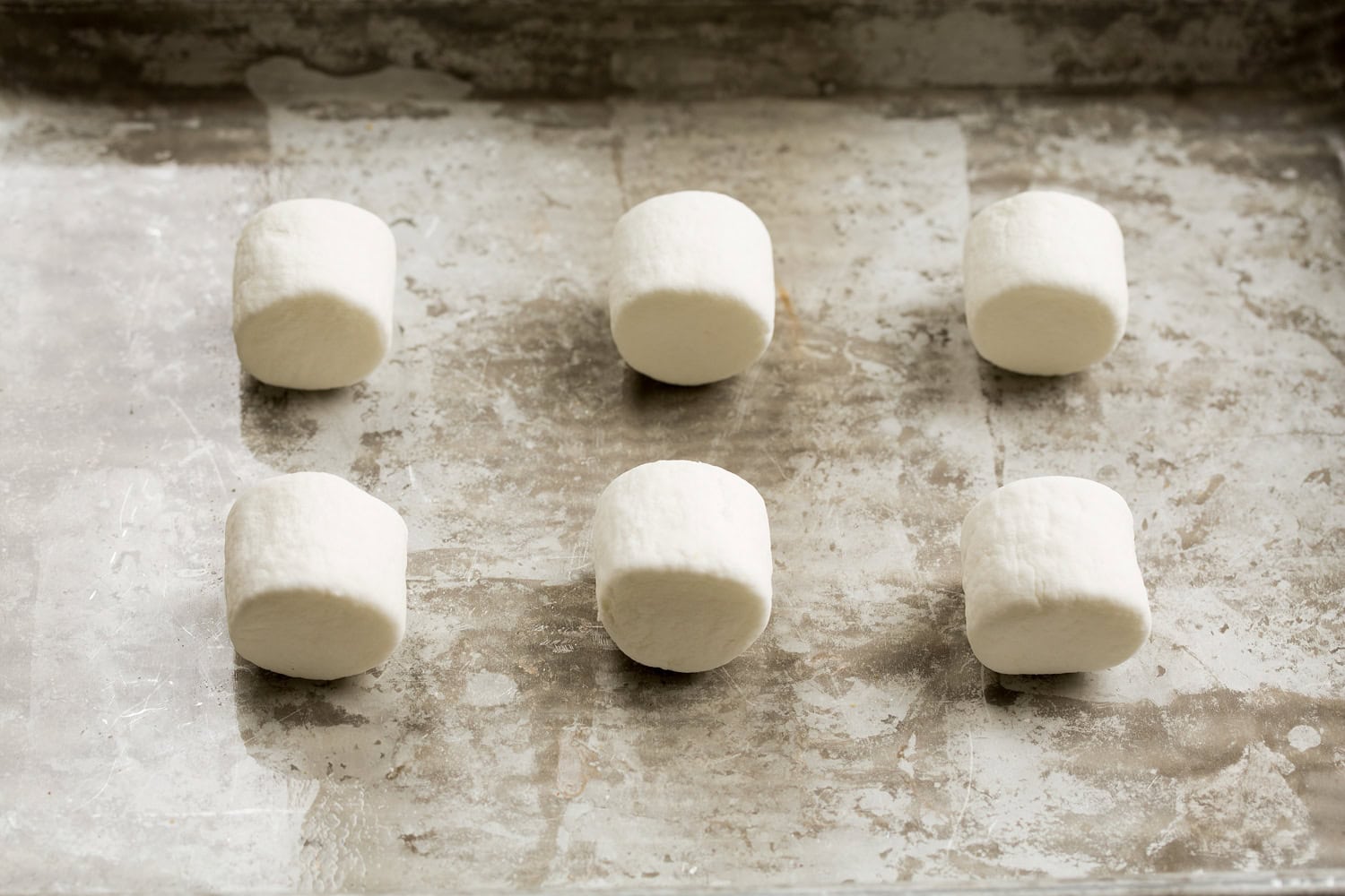 Plain untoasted marshmallows on a baking sheet.