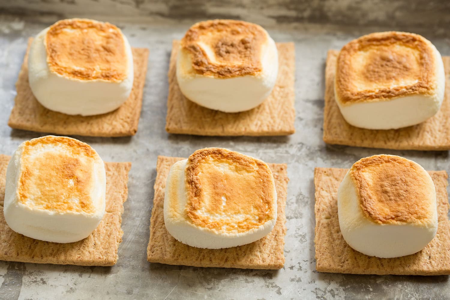 Marshmallows on graham cracker shown toasted on second side.