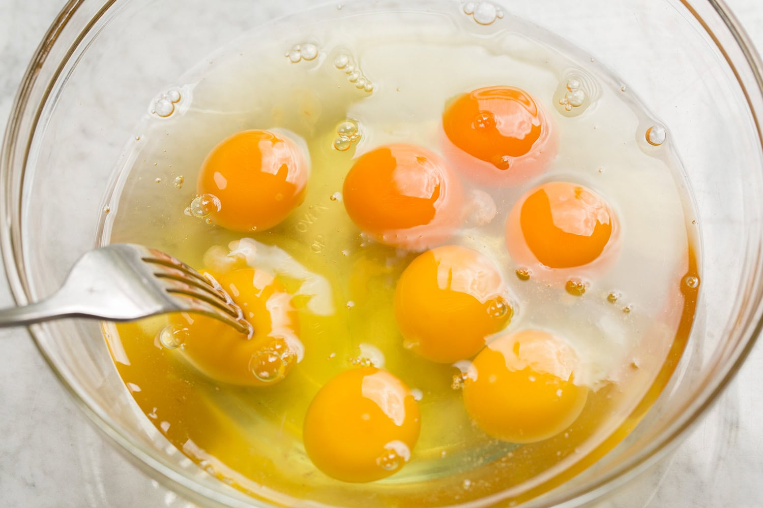 Cracked eggs in a bowl shown before scrambling.