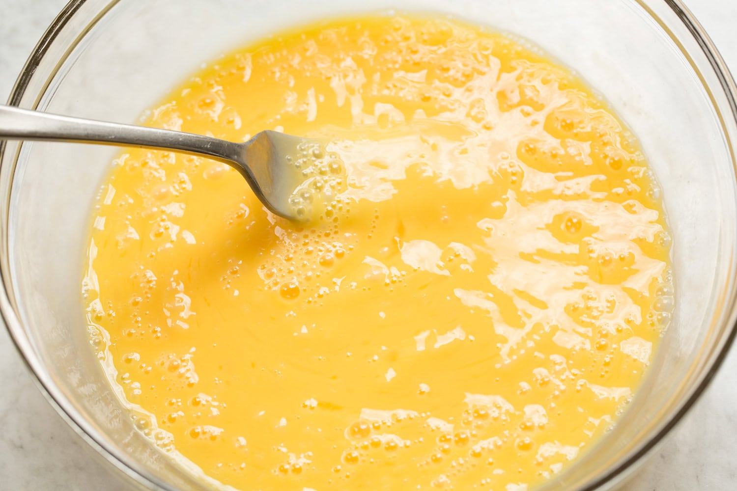 Eggs in a bowl shown scrambled with a fork.