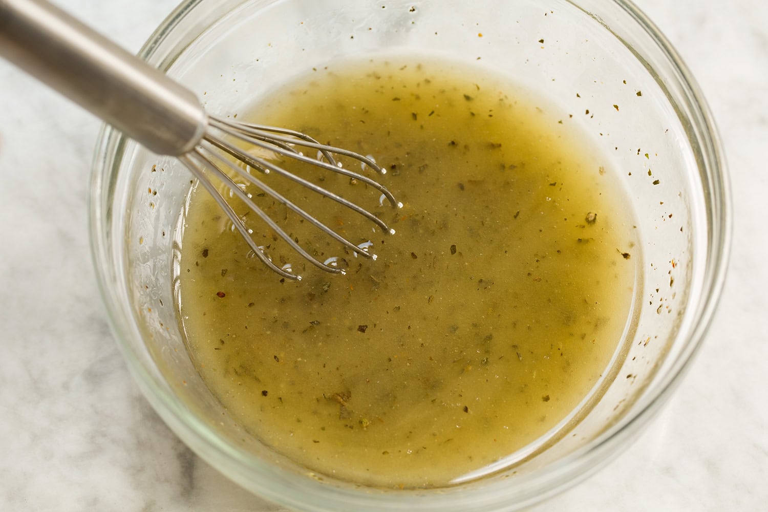 Dressing for pasta salad being mixed together in a glass dish.