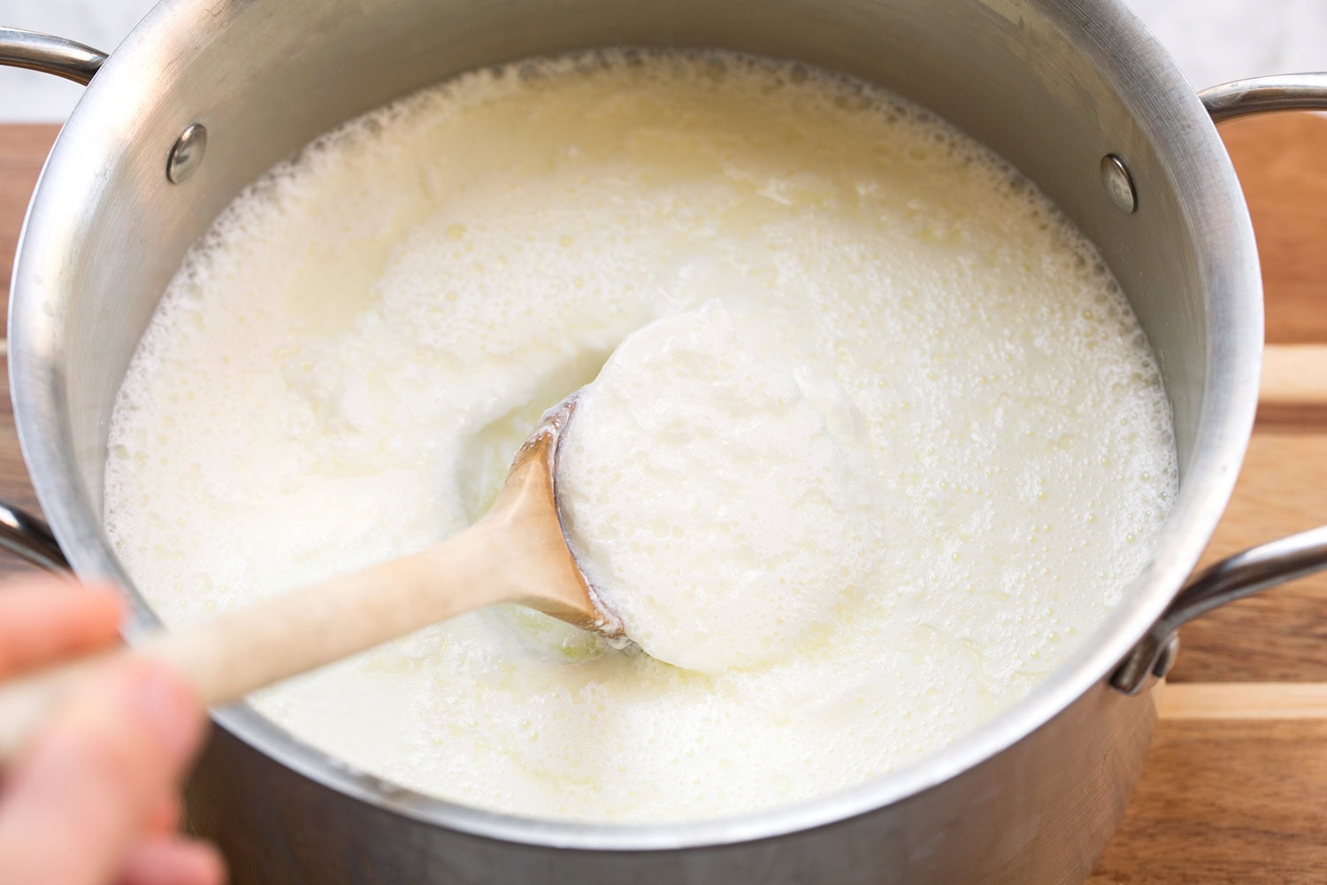 Yogurt shown after setting overnight with a spoon scooping some out.