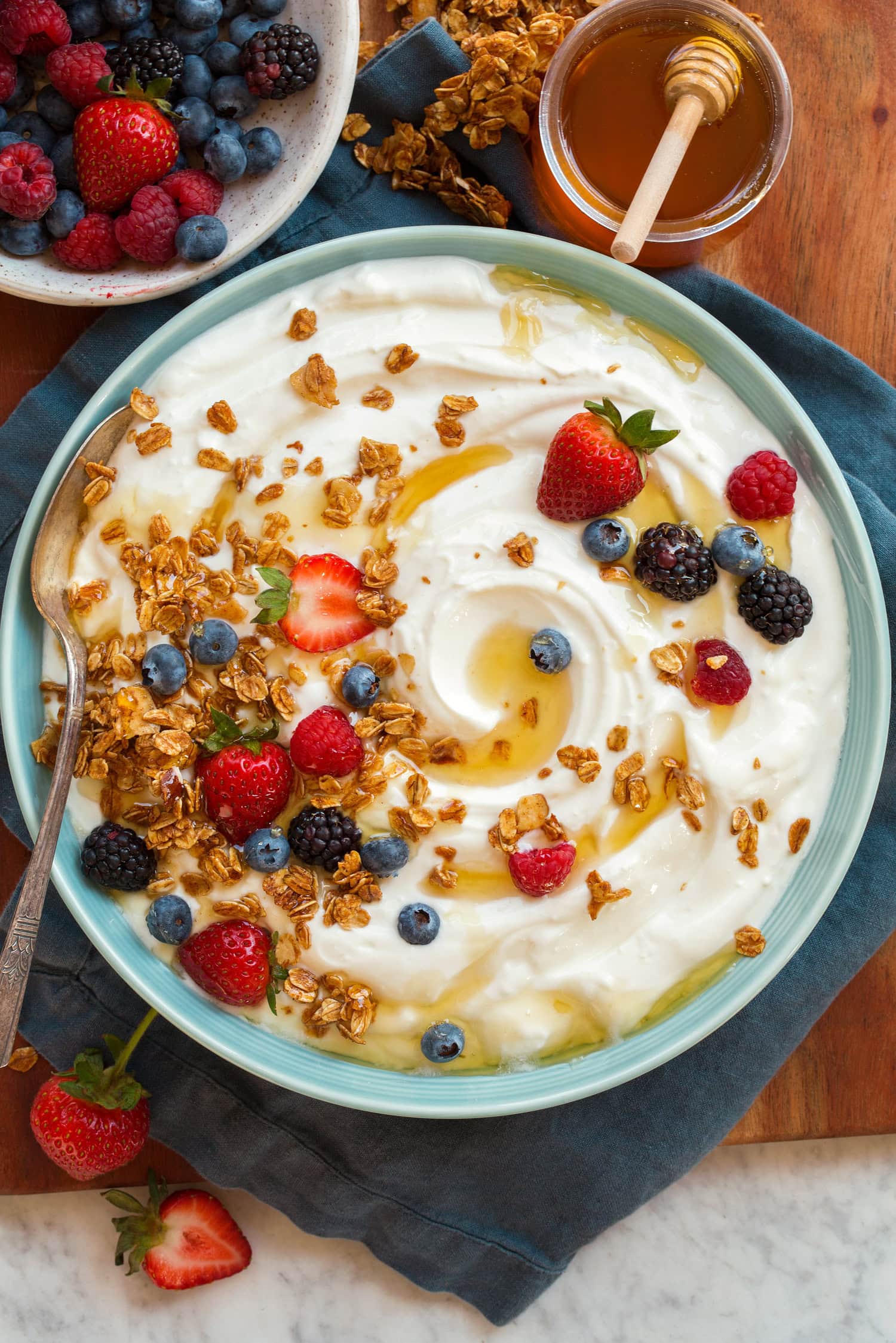 Plain homemade yogurt with fruit and granola atop. Shown from overhead.